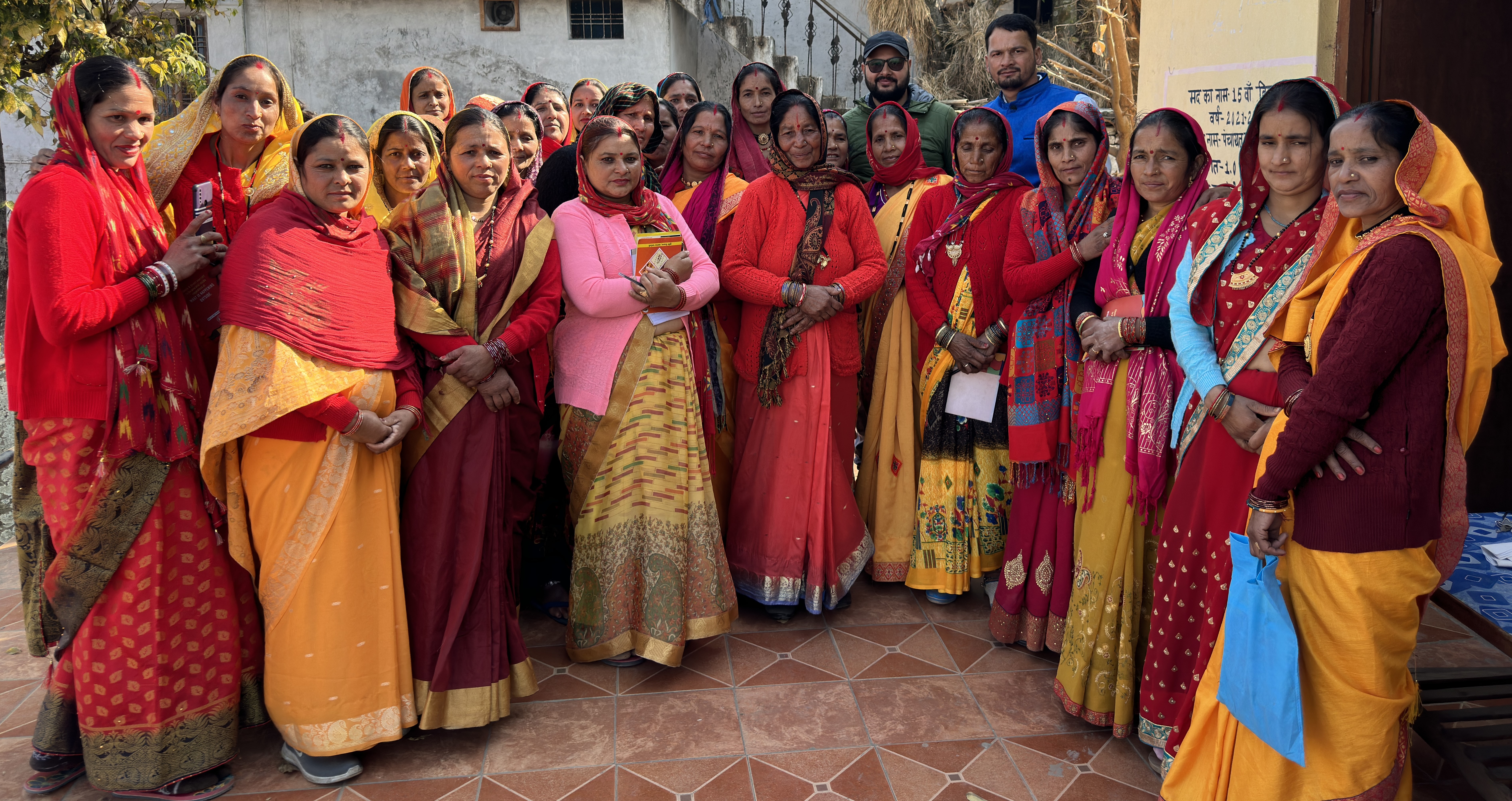 Women stand together outside a community training venue for a group photograph.